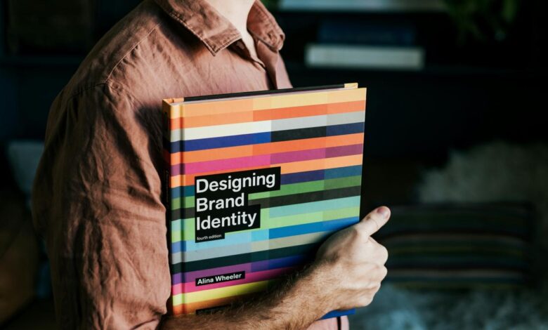 a man holding a book that says designing brand identity