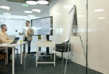 Man presenting to colleagues in a modern office meeting.