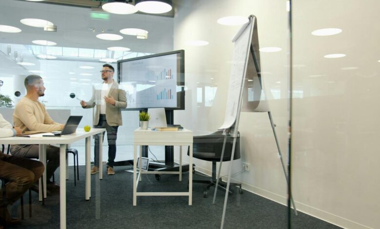 Man presenting to colleagues in a modern office meeting.