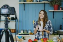 Woman filming herself cooking in a kitchen.